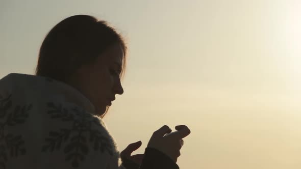 Beautiful Girl Standing at Dawn and Using Phone