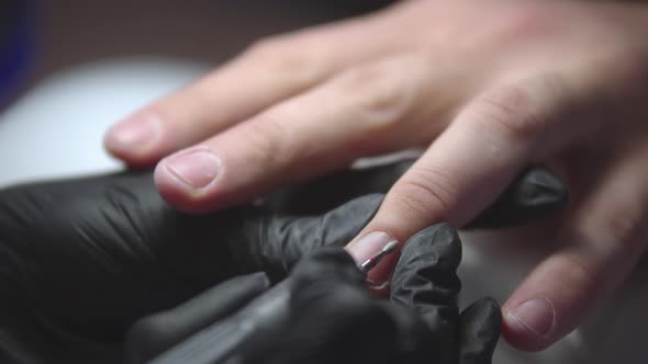 Manicurist Doing Man's Manicure Using Small Drilling Device  Cleaning Out Cuticle Zone