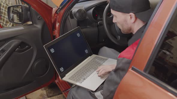 Mechanic Doing Diagnostic Test on Car with Laptop