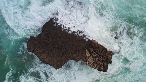 Ocean rock battered by waves in Praia Do Tonel, near Cape Sagres Portugal, Aerial top view lowering