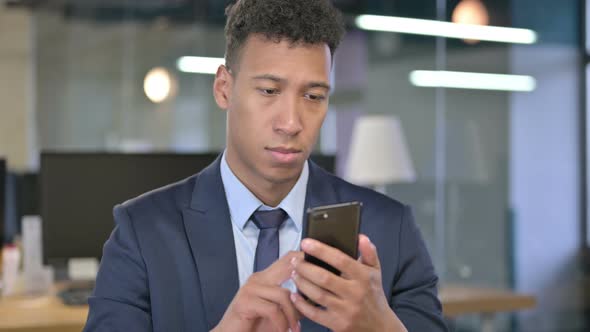 African Businessman Using Smartphone in Office
