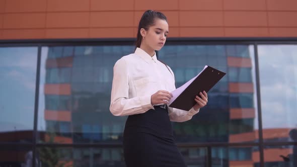 A Business Woman is Looking at Working Papers While a Businessman and a Business Woman are Taking