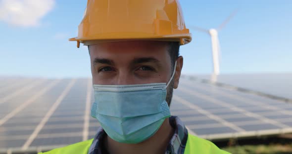Young man working at solar power station while wearing safety face mask