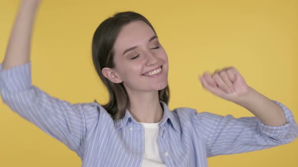 Happy Young Woman Dancing on Yellow Background