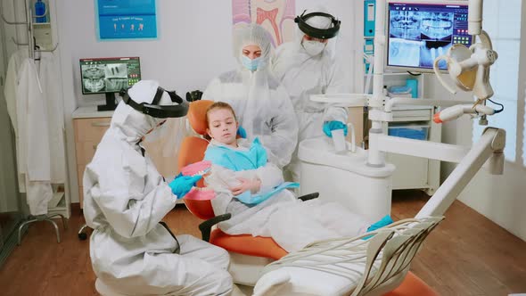 Dentist Doctor in Coverall Showing To Kid the Correct Dental Hygiene