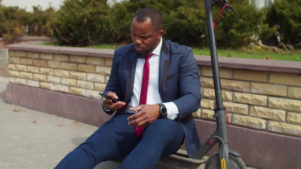 Businessman Sitting on Escooter Talking on Smartphone