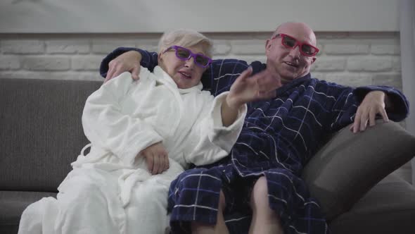 Close-up of Joyful Caucasian Mature Man and Woman Sitting on Couch and Watching 3D Movie. Modern