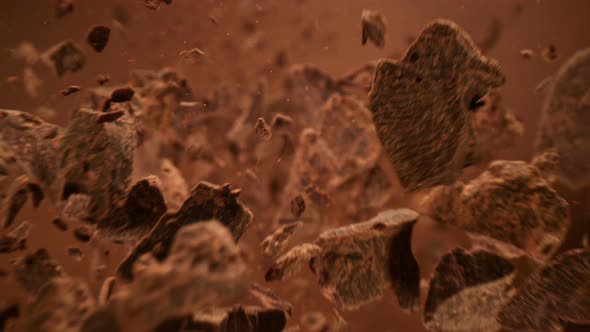 Super Slow Motion Detail Shot of Falling Raw Chocolate Chunks on Brown Background at 1000Fps