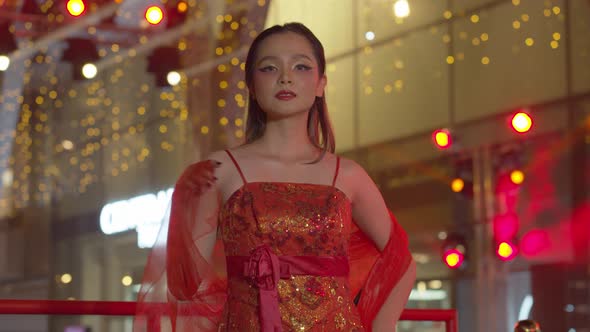 Beautiful Asian woman dressed to celebrate the Chinese New Year poses in her red sleeveless dress wi