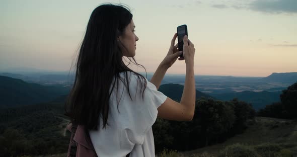 Influencer or Blogger on Top of Mountain Making Photo or Video on Hike Journey