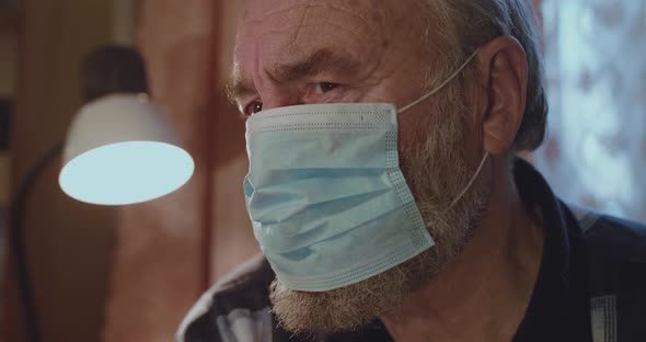 Portrait of Sad Older Man in Medical Mask Thoughtfully Looks at Camera