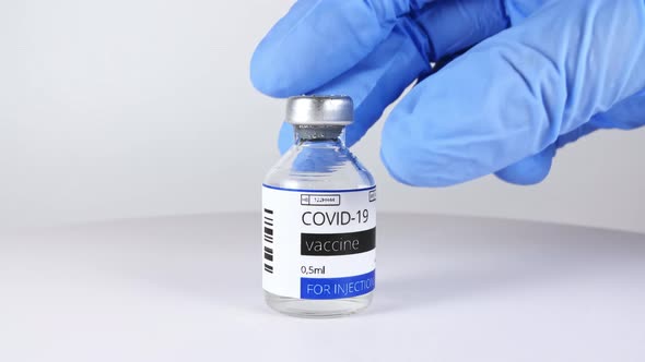 COVID19 Vaccine in Researcher Hands Doctor Puts on the Table Bottle with Vaccine for Coronavirus