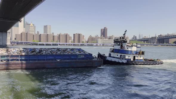 Tugboat pushing New York trash barge filled to the brim; aerial