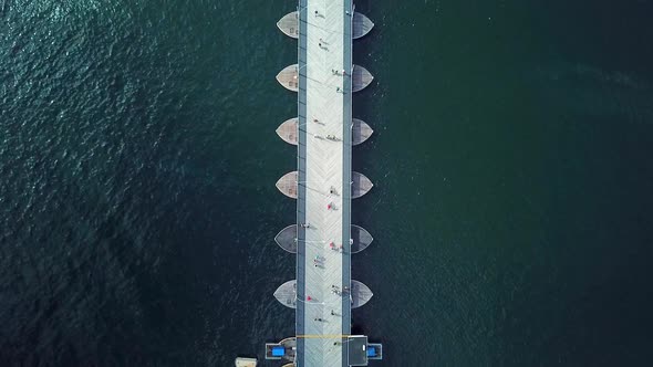 Overhead dolly-in aerial view of the Queen Emma Bridge in St. Anne's Bay, people passing over it, Wi