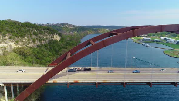 Minor traffic moving from left to right on the Pennybacker Bridge with a view of the city of Austin,