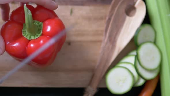 Male is preparing food in kitchen at home. Topview shot of man cutting vegetables on chopping board.