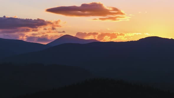 Beautiful Evening Panoramic Landscape with Bright Setting Sun Over Distant Mountain Peaks at Sunset