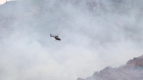 Helicopter flying over wildfire to see the progress of the firefighters alt