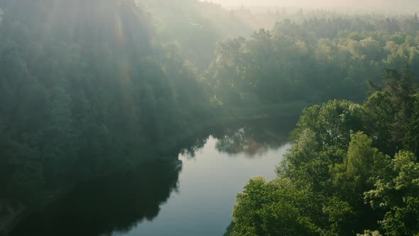 Sunny green countryside with river at morning, tracking drone shot