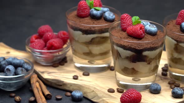 Classic Tiramisu Dessert with Blueberries and Raspberries in A Glass on Wooden Cutting Board
