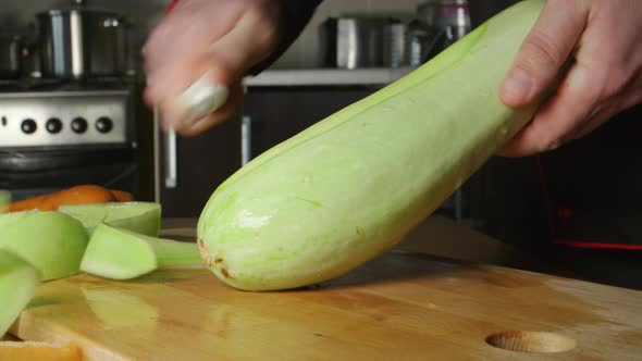 A Cook Cleans A Vegetable Marrow On A Cutting Board In A Restaurant Kitchen