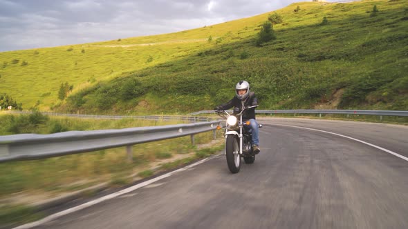 Man Riding Motorcycle In Asphalt Road Curve With Rural