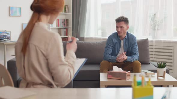 Man Talking to Therapist Taking Notes