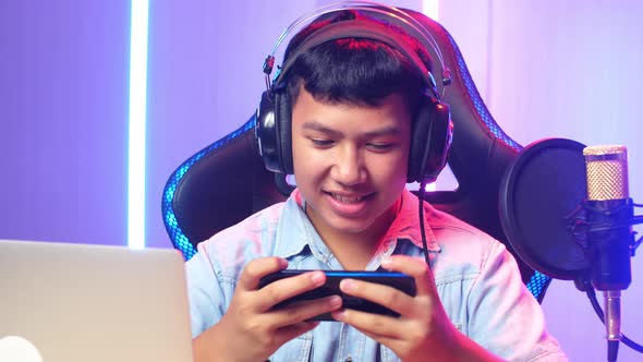 Excited Asian Kid Boy Playing Video Game With Mobile Phone While Live Stream