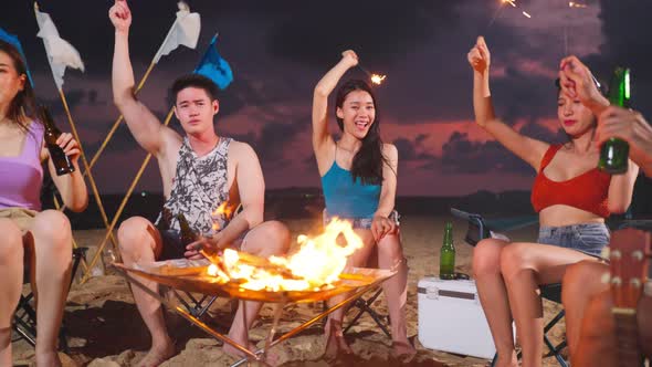 Group of Asian young man and woman having party on the beach at night.