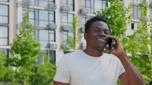 Portrait Smiling Positive Afroamerican Man Talking on Mobile Phone in Park