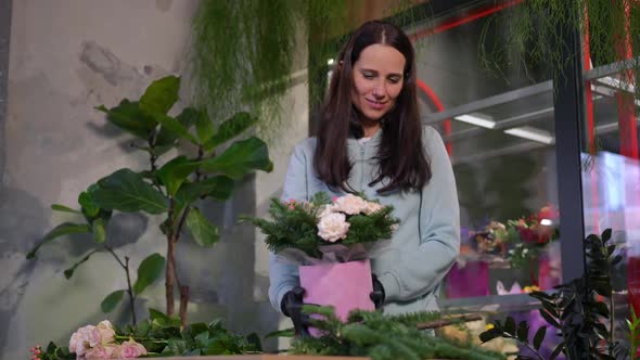 Satisfied Florist Admiring Bouquet Standing in Workshop Smiling