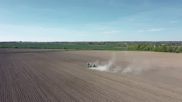 Aerial view of farming tractor plowing a field, at sunny day