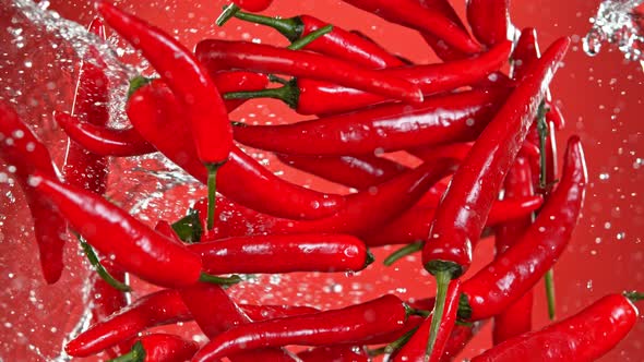 Super Slow Motion Shot of Flying Fresh Chilli Peppers and Water Side Splash at 1000 Fps