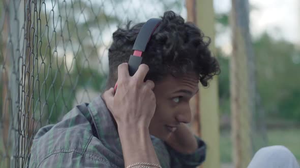 Side View Close-up of Cheerful Happy African American Man Putting on Headphones and Smiling