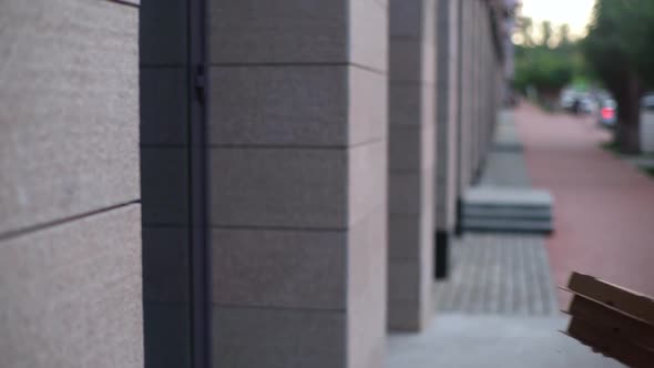 Hand held shot of delivery man coming to door and rings doorbell. Courier holding boxes with pizza