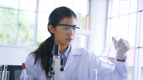 Young Female Asian Medical Researcher Work in Pharmacy Laboratory While Mix Chemical in Flask Tube