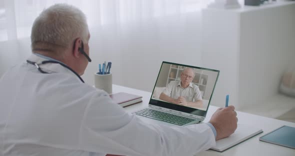 Male Doctor Is Communicating with His Patient Online, Elderly Man Is Talking About Symptoms 