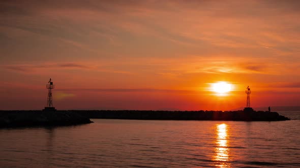 High Lighthouse Silhouette on Rocky Cliff at Calm Sea Against Sunset