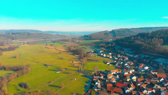 drone flight over a small village with lake in the background on a sunny day