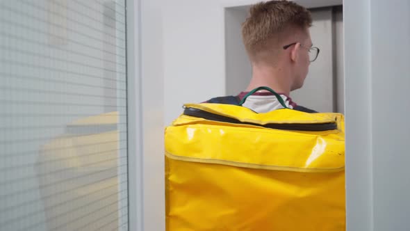 Young Courier Pressing Elevator Button Standing Indoors Waiting for Lift in Business Center