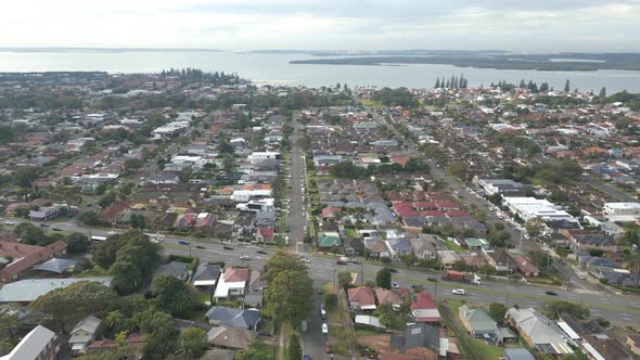 Aerial view of intersection with busy car traffic in the residential area, houses or home and ocean