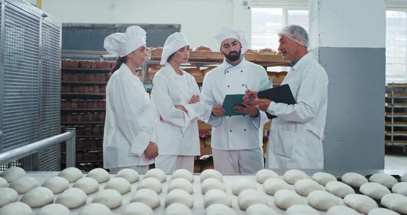 In a Bakery Factory Two Bakers Chef One Assistant