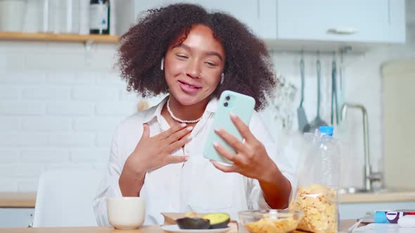 Happy African American Woman Makes Video Call on Phone During Breakfast