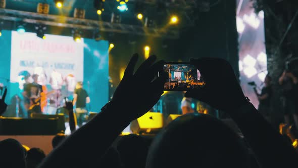 Male with Smartphone in Hand Making Video at Live Rock Concert. Slow Motion