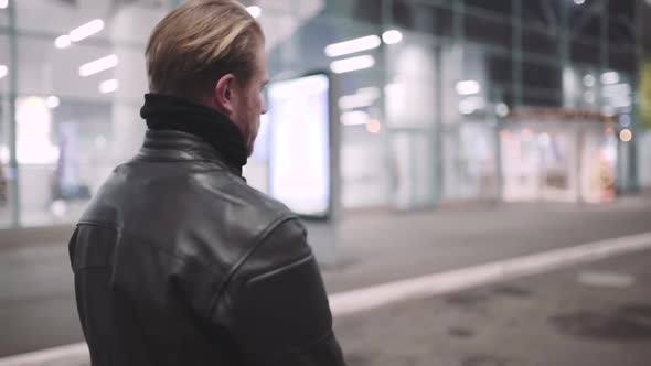 A Young Man Goes to His Motorcycle Sits on It and Puts a Helmet to Go on a Journey at Night Street