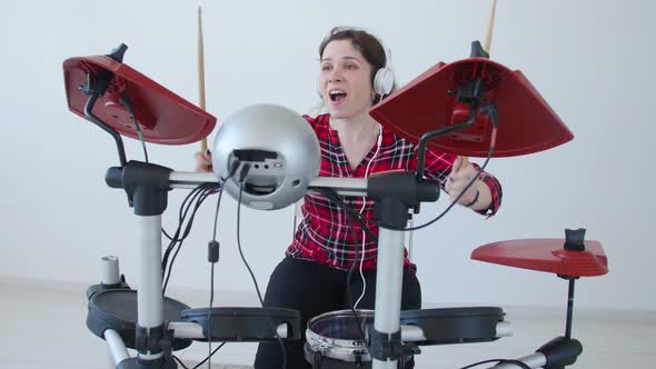 Concept of Hobby and Music. Young Woman Drummer Practicing Electronic Drum Kit at Home