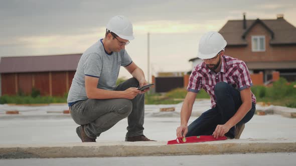 Two Builders Check the Accuracy of Building the Base of the Building