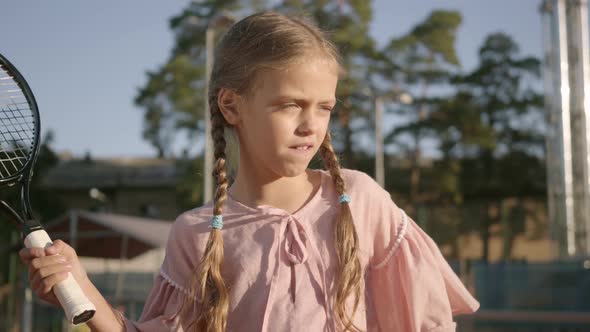 Portrait Adorable Funny Girl with Two Pigtails Playing Tennis Outdoors