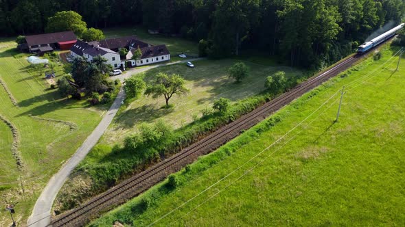 Aerial view of a diesel train passing in front of the farmhouse. A railway line running through the