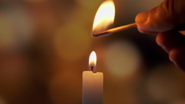 Footage of Using a Match Light a Candle on on a of Colored Blurred Bokeh